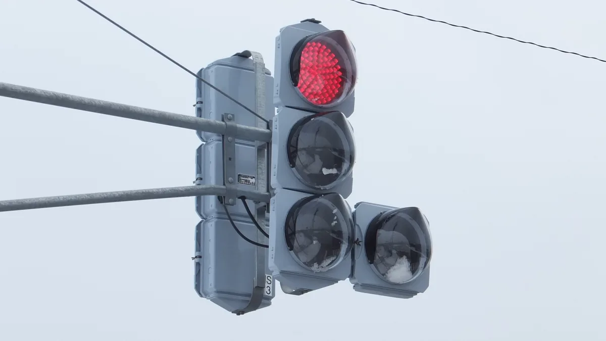秋田市の縦型信号機。3つの灯火が縦に並び、それぞれにお椀型の透明なフードが付いている。下の2灯と矢印灯には雪が付着している